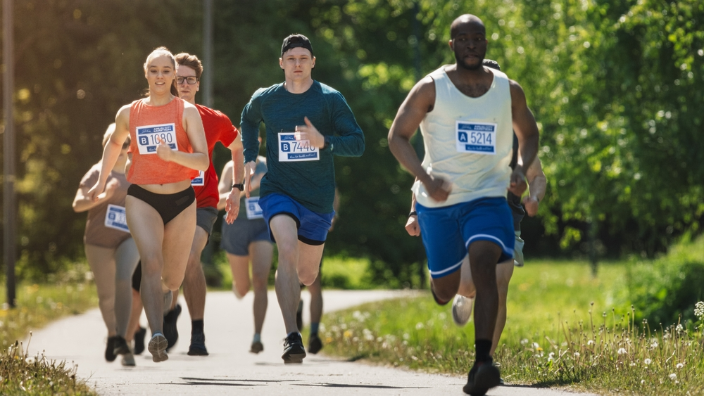 Runners wearing race bibs on a park trail